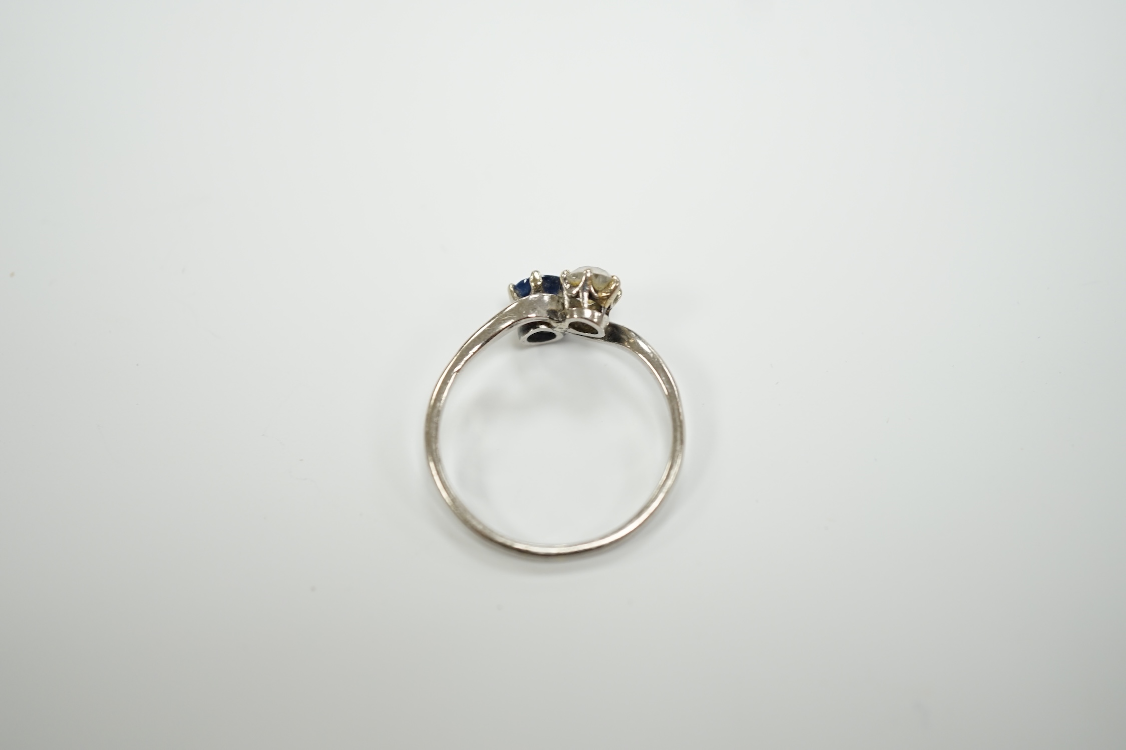 A mid 20th century white metal (stamped plat), sapphire and diamond set two stone crossover ring, size Q, gross weight 3.2 grams.